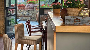 A cozy patio area with a stone wall, a wooden table, and two striped chairs.