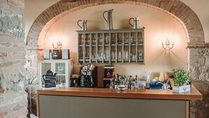 A rustic bar area with a brick archway, wooden beams, and a bar counter with stools.