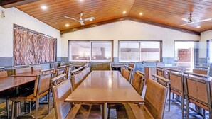 A spacious dining area with high ceilings, wooden beams, and large windows.