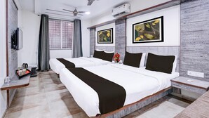 A hotel room with two beds, a ceiling fan, an air conditioning unit, a TV, and artwork on the walls.