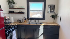 A compact kitchen with a window, wooden countertops, and dark cabinets. - Cozy Cottage House in Louisville (Louisville)