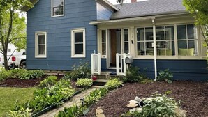 Une maison à deux étages, avec une façade bleue et une véranda.