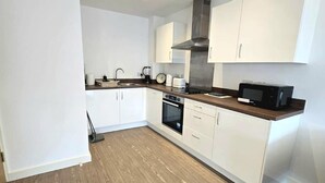 A modern kitchen with white cabinets, a stainless steel range hood, a microwave, and a built-in oven.