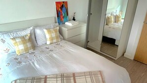 A bedroom with a bed, nightstand, and a mirror.