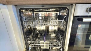 An open dishwasher with multiple racks and a control panel on the right.
