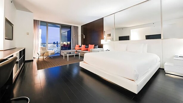 A modern hotel room with a large bed, a desk, a sofa, and a balcony with a city view. - Palms Place Hotel StripView (Las Vegas)