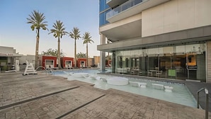 A rooftop pool area with lounge chairs and a bar, surrounded by palm trees and modern buildings. - Palms Place Hotel StripView (Las Vegas)