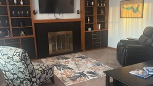 A living room with a fireplace, a television, a bookshelf, and a leather sofa.
