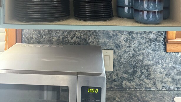 A kitchen with a microwave and a digital clock displaying 0:00.