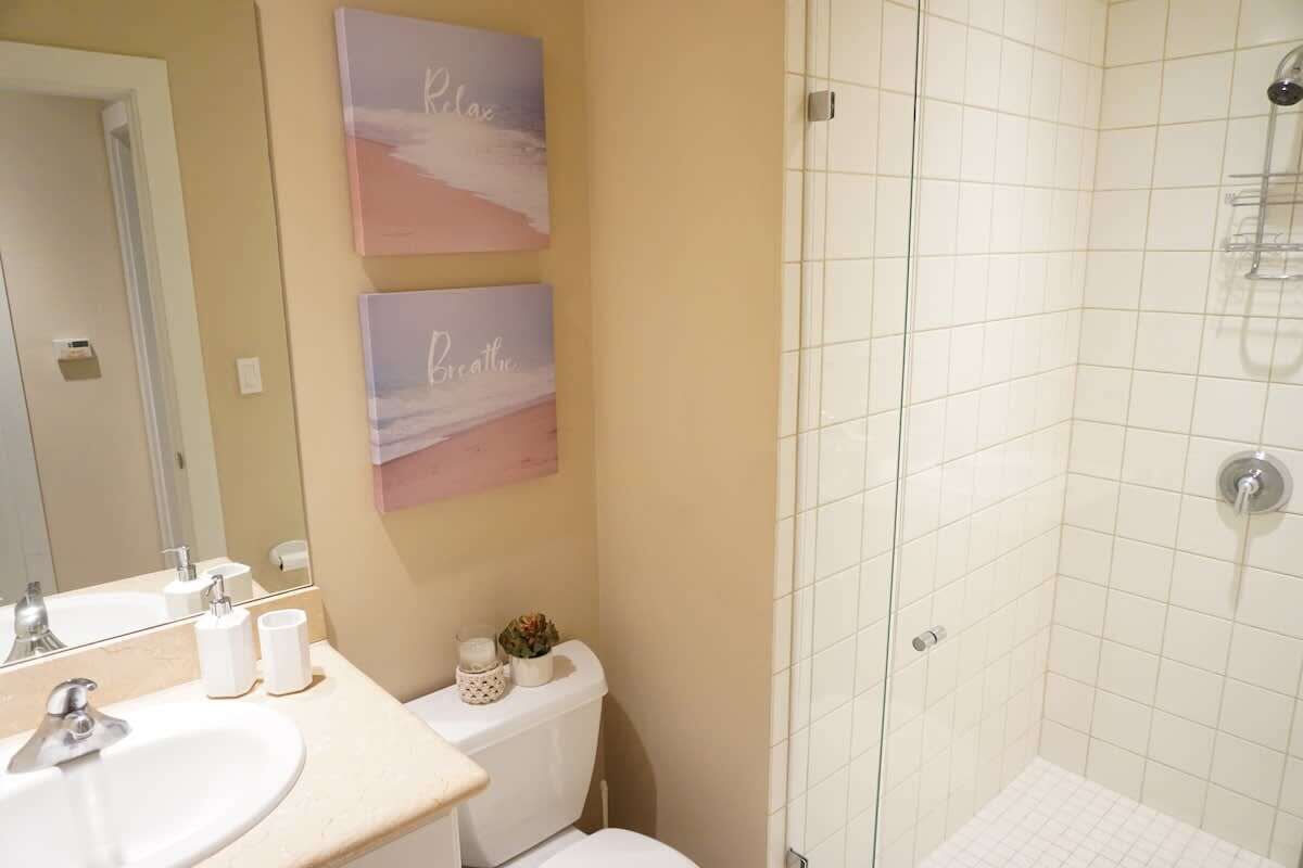 Een badkamer met een wastafel, toilet en douche. Twee wandborden met de woorden 'Relax' en 'Breathe'.