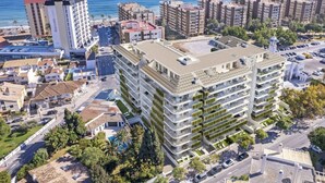 A high-rise hotel with multiple balconies, a rooftop pool, and a view of the sea. - Happy Travel Jade Tower (Fuengirola)