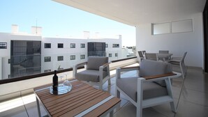 A balcony with a wooden table, two white chairs, and a bottle of wine. - Happy Travel Daphne Higueron (Fuengirola)