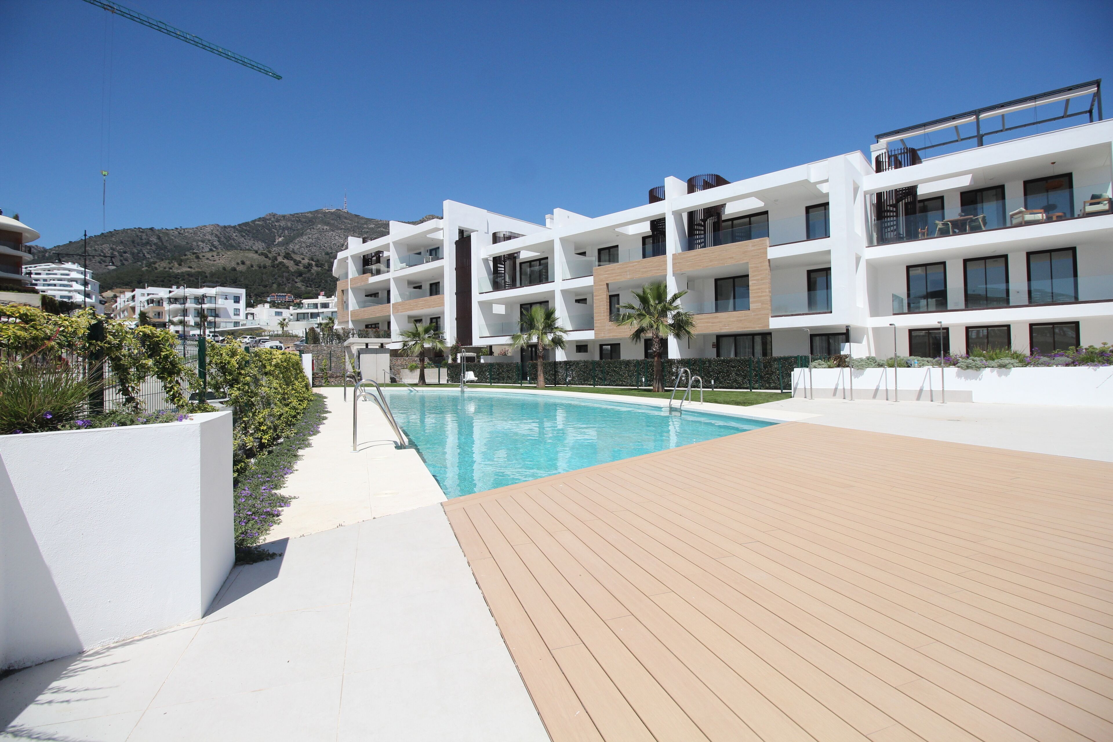 Ein modernes Hotel mit Schwimmbad, heller Fassade und Balkonen.