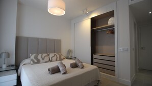 A modern bedroom with a large bed, bedside tables, a wardrobe, and a hanging light fixture. - Happy Travel Jasmine Higueron (Fuengirola)