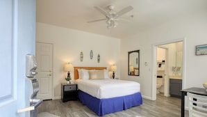 A bedroom with a bed, nightstands, a ceiling fan, and a bathroom visible through an open door.