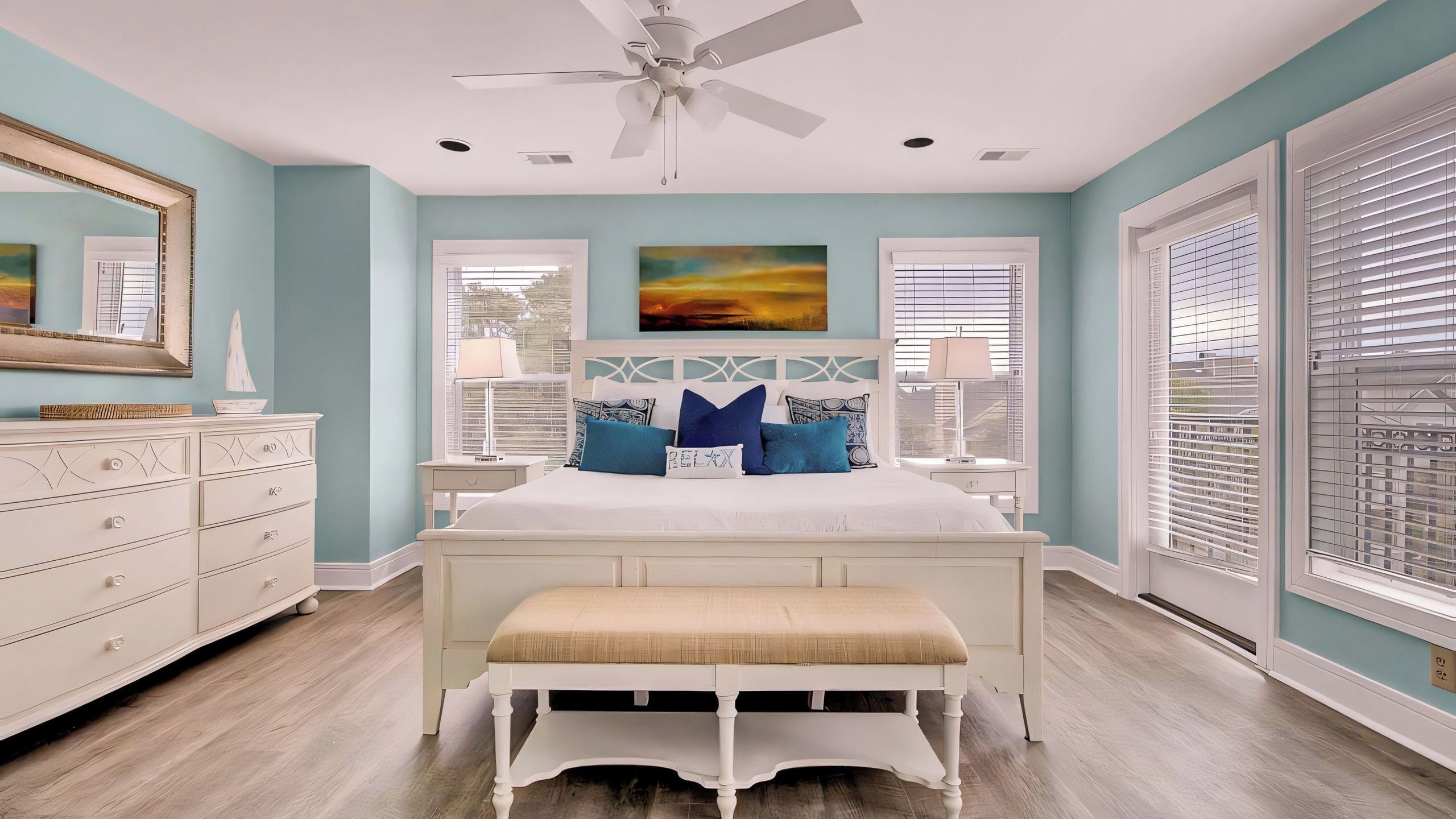 A bedroom with a bed, a bench, a dresser, a ceiling fan, and a window with blinds.