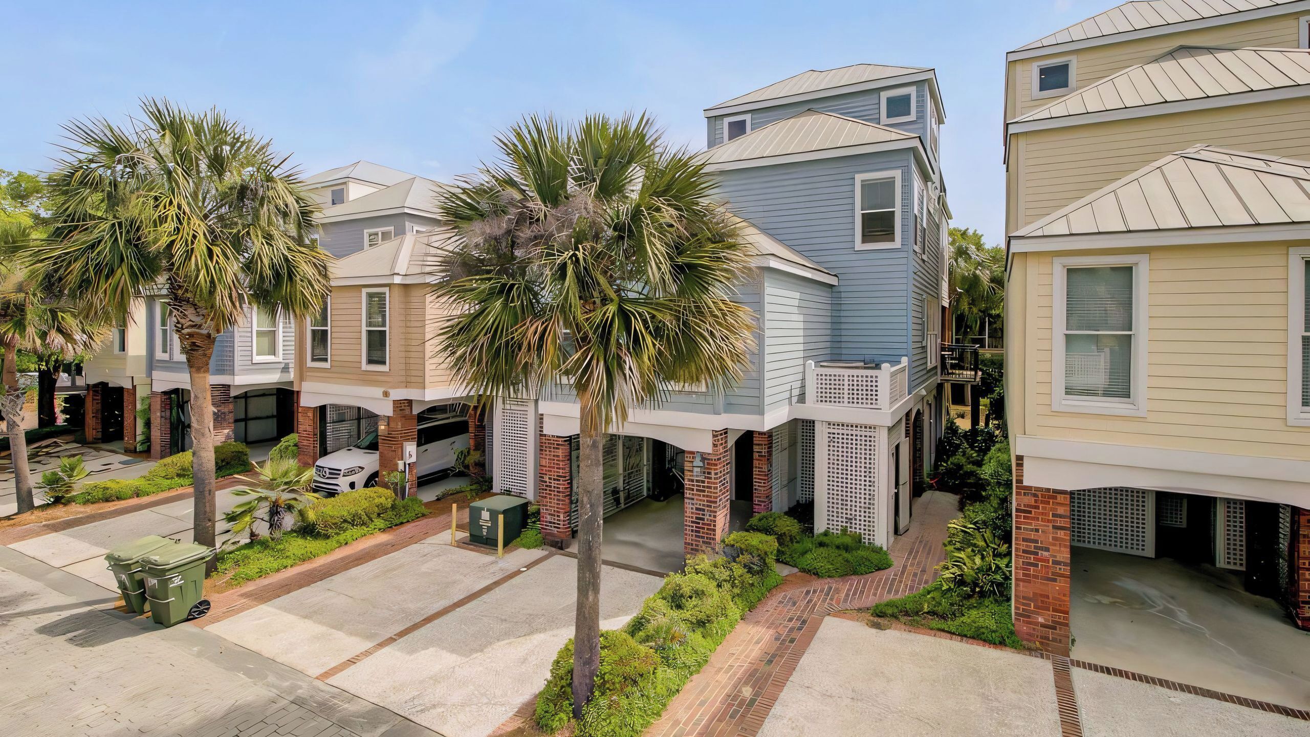 A residential area with modern houses, a driveway, and palm trees.