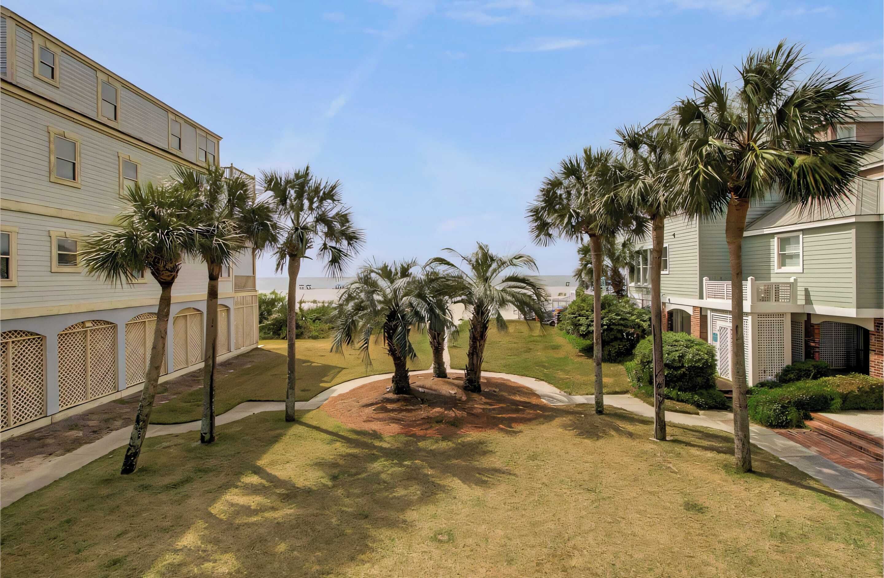 A courtyard with palm trees, a building with a light-colored facade, and a brick structure.