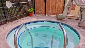 Una piscina pequeña y circular con borde de azulejos azules y una escalera metálica.