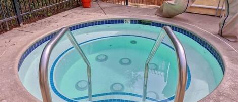Una piscina pequeña y circular con borde de azulejos azules y una escalera metálica.