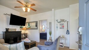 A living room with a fireplace, a television, and a ceiling fan.