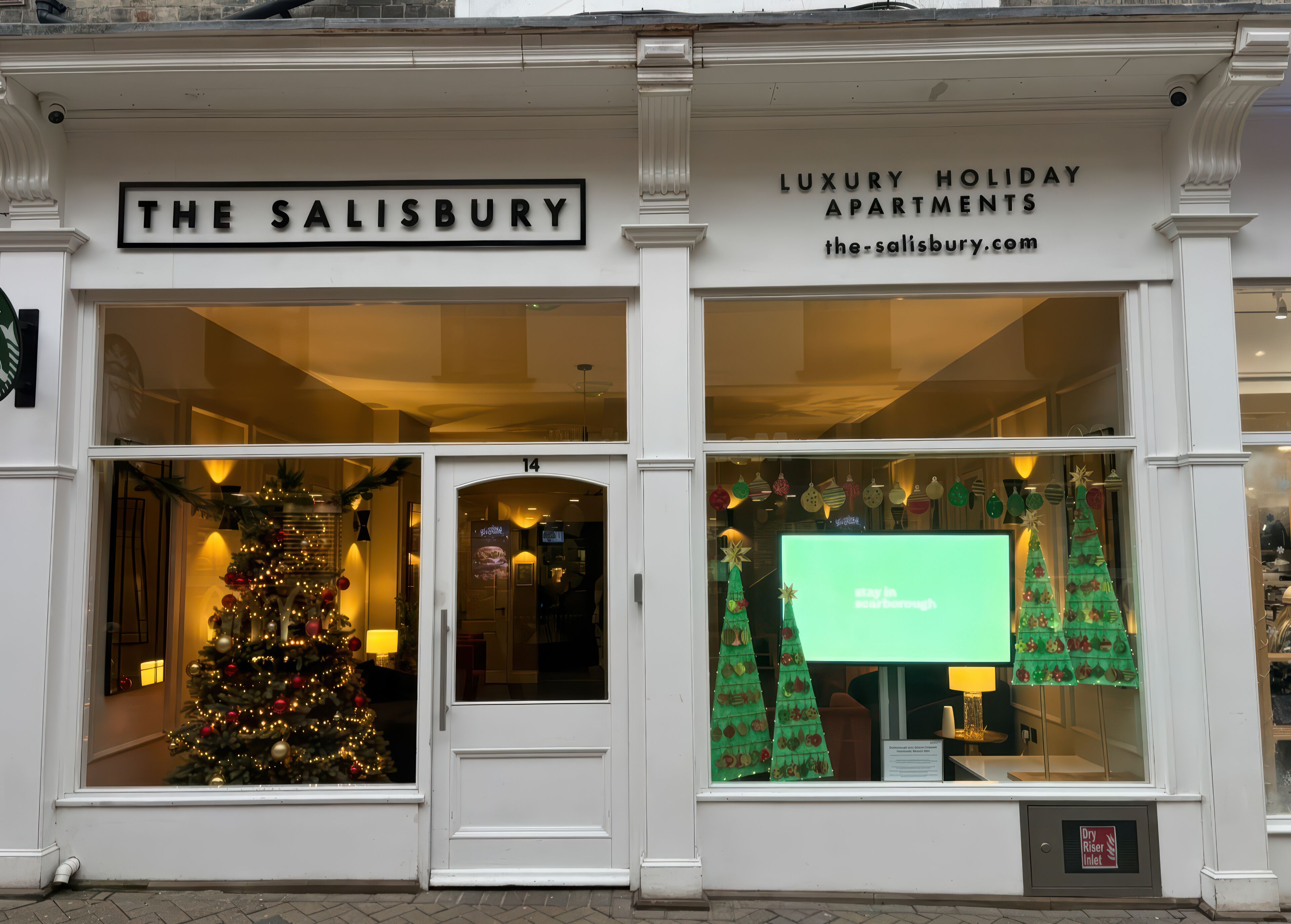 A building with a sign reading 'THE SALISBURY LUXURY HOLIDAY APARTMENTS' and a website address.