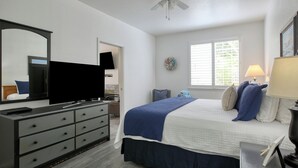 Un dormitorio con cama, cómoda, televisor y ventilador de techo.