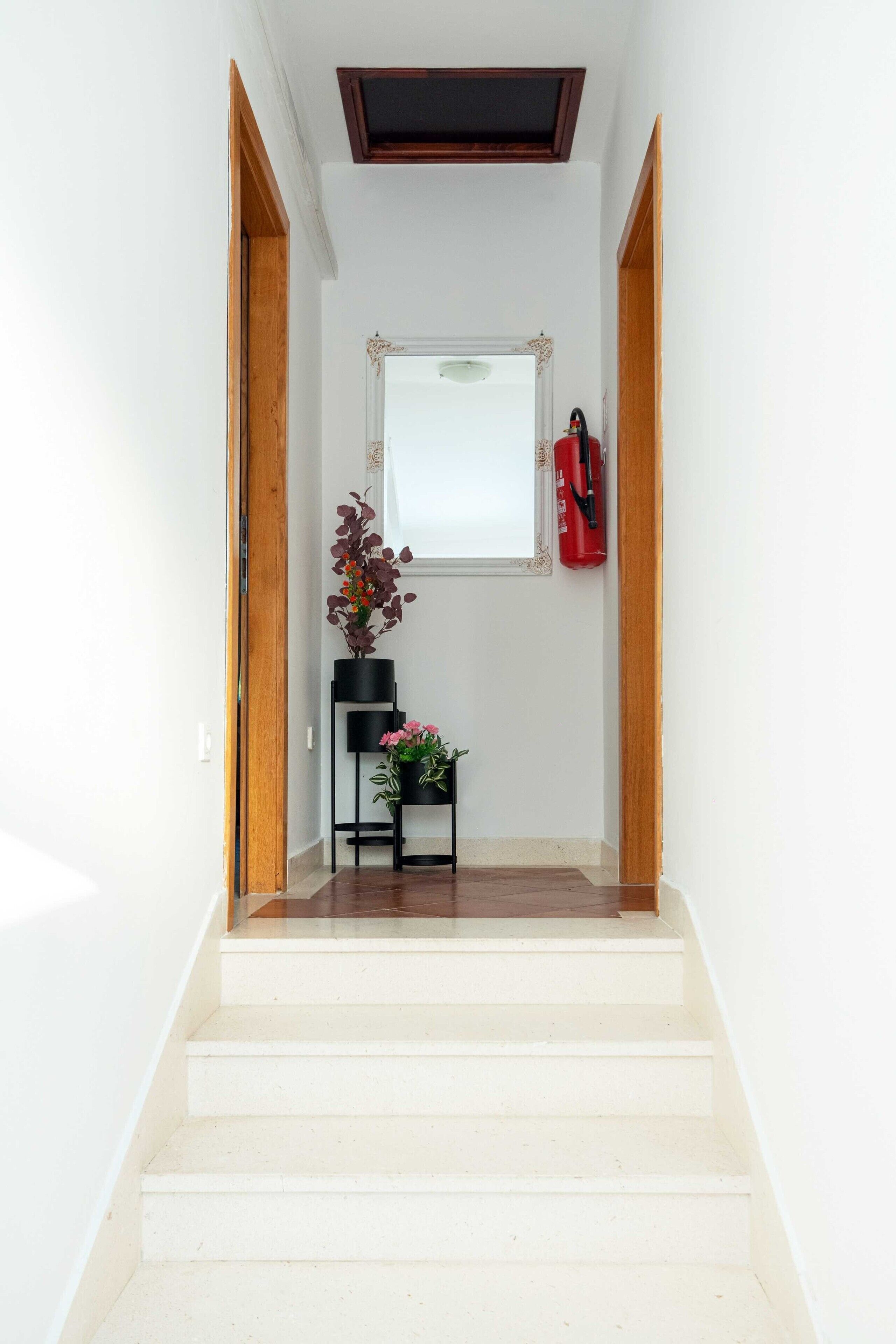 Eine Treppe führt zu einer Empore mit einem gerahmten Bild und einem Feuerlöscher an der Wand.