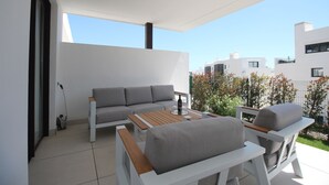 A modern outdoor living area with a sofa, two chairs, and a table. - Happy Travel Lily Home Higueron (Fuengirola)