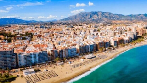 A coastal cityscape with a beach, buildings, and mountains in the background. - Happy Travel Lily Home Higueron (Fuengirola)