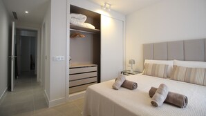 A modern bedroom with a large bed, a walk-in closet, and a bedside table with a lamp. - Happy Travel Lily Home Higueron (Fuengirola)