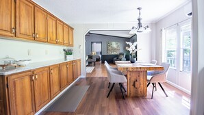 Une cuisine spacieuse avec des meubles en bois, un îlot central doté de chaises et une vue sur l’espace repas.