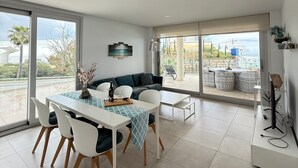 A modern dining area with a table set for two, a sofa, and a view of the outdoors. - Happy Travel Panoramica (Fuengirola)