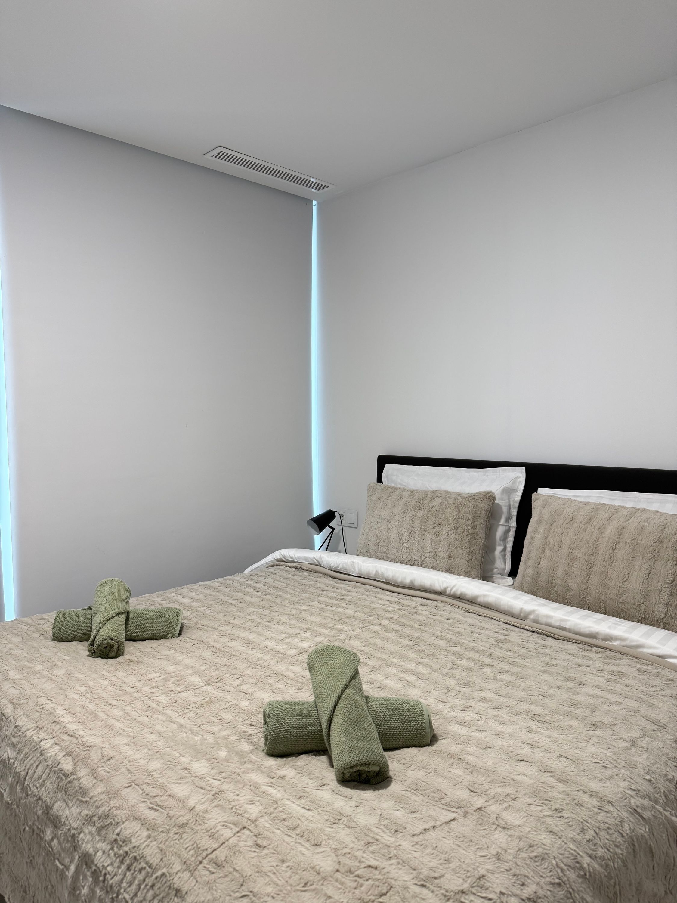 Ein ordentlich bezogenes Bett mit einer gesteppten Decke, zwei Kissen und zwei aufgerollten Handtüchern.