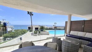 A round table with a tray and two cups, surrounded by wicker furniture, overlooking a pool and the ocean. - Happy Travel Panoramica (Fuengirola)