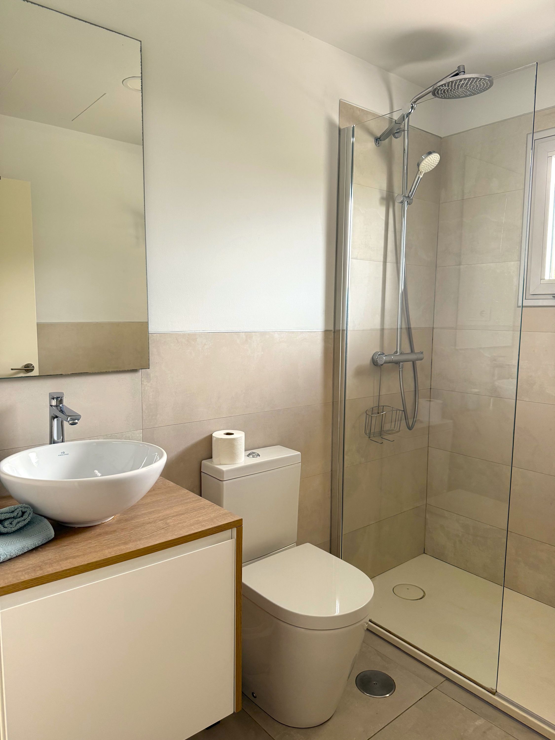 Ein modernes Badezimmer mit einem großen weißen Waschbecken, einer Toilette und einer gläsernen Duschkabine.