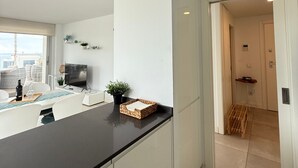A modern kitchen with white cabinetry, a black countertop, and a small island with a plant. - Happy Travel Panoramica (Fuengirola)