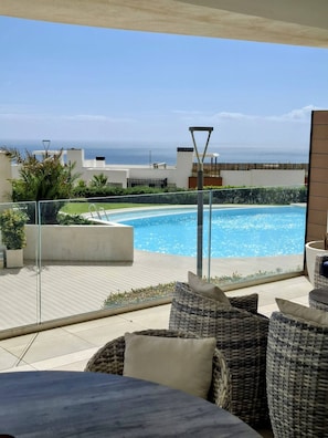 A poolside area with a view of the sea, wicker furniture, and a clear sky. - Happy Travel Panoramica (Fuengirola)
