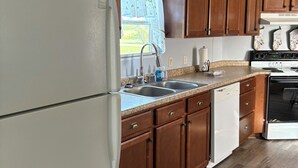 A kitchen with wooden cabinets, a stainless steel sink, a dishwasher, and a stove.