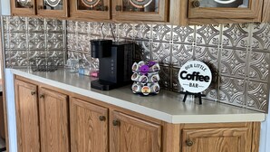 A kitchen with wooden cabinets, a coffee maker, and a coffee sign.