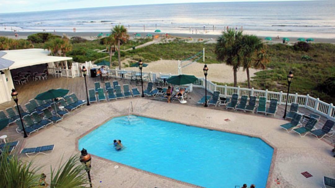 Un espace piscine avec des chaises longues, une petite piscine et une vue sur la plage.