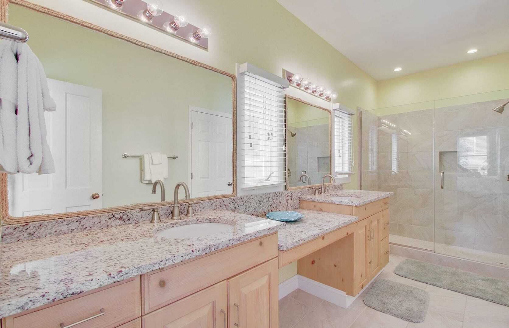 A bathroom with two sinks, a large mirror, and a shower area.