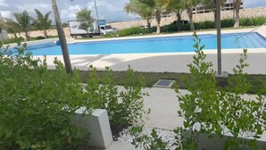 A swimming pool with palm trees and a stone building in the background.