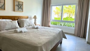 A neatly made bed with a quilted bedspread, a wooden headboard, and two framed starfish artworks on the wall.