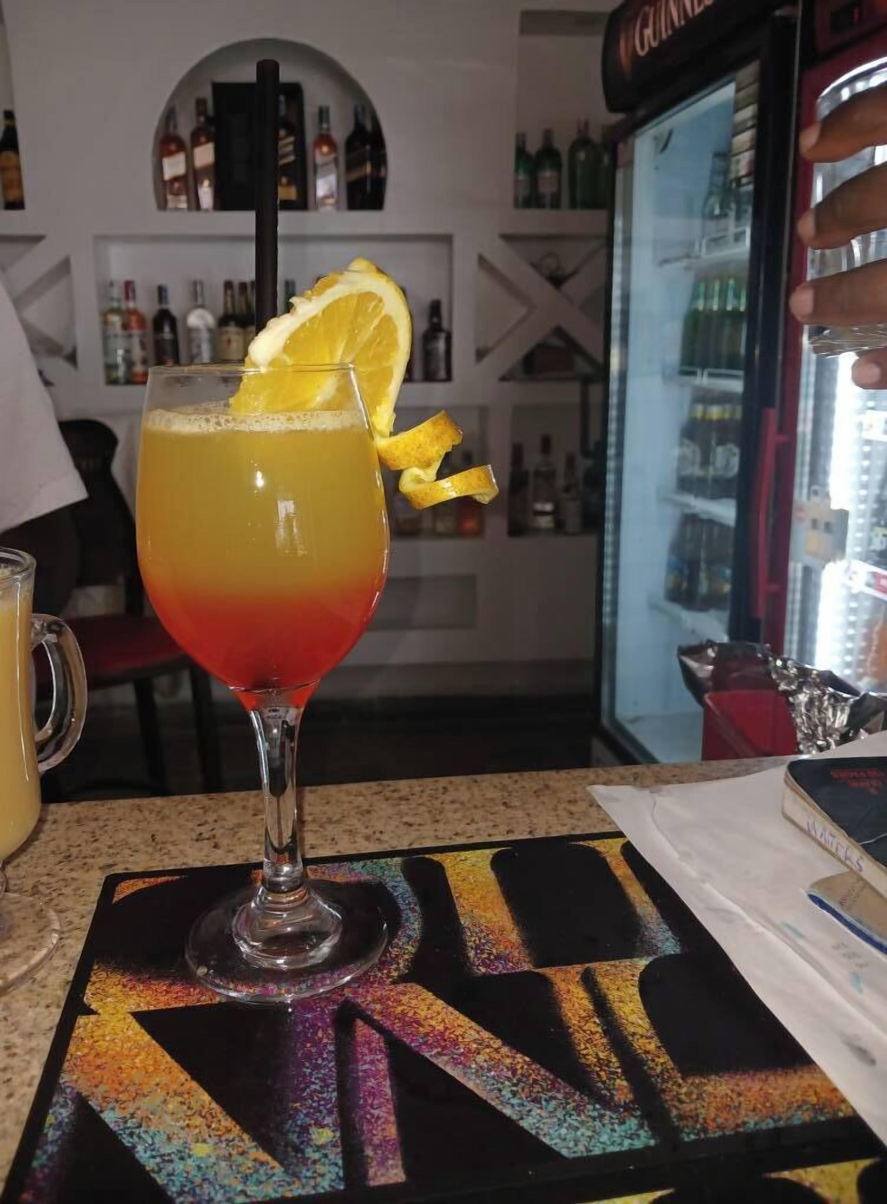 A cocktail with a gradient color and a lemon slice garnish on a bar counter.
