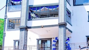 A multi-story building with a balcony, large windows, and decorative columns. - The Grand Alton resort (Kisumu)