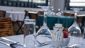 A dining table set with clear glassware, a white vase with gold accents, and a small potted plant. - The Grand Alton resort (Kisumu)