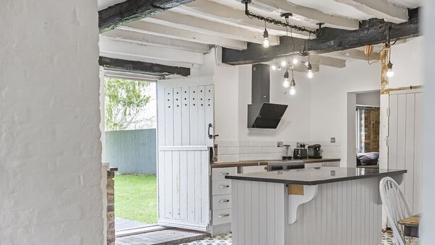 A kitchen with a central island, white cabinetry, and a patterned floor. - 3 Bedroom Country Cottage with Private Fenced Garden (Shifnal)