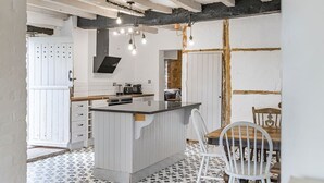 A kitchen with a central island, white cabinetry, and a patterned floor. - 3 Bedroom Country Cottage with Private Fenced Garden (Shifnal)