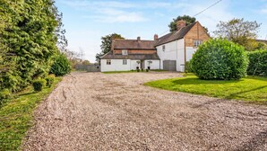A gravel driveway leading to a two-story house with a white exterior and a brick chimney. - 3 Bedroom Country Cottage with Private Fenced Garden (Shifnal)